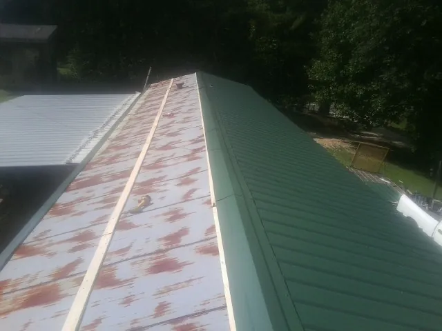 Old rusted panels beside newly installed green metal roofing — Wind Damage Roof Repair by Roofing Brothers in Ringtown