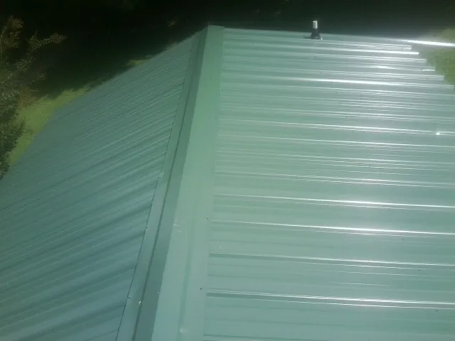 New green metal panels meeting at the ridge of a roof — Flat Roof Repair work by our crew in Ringtown