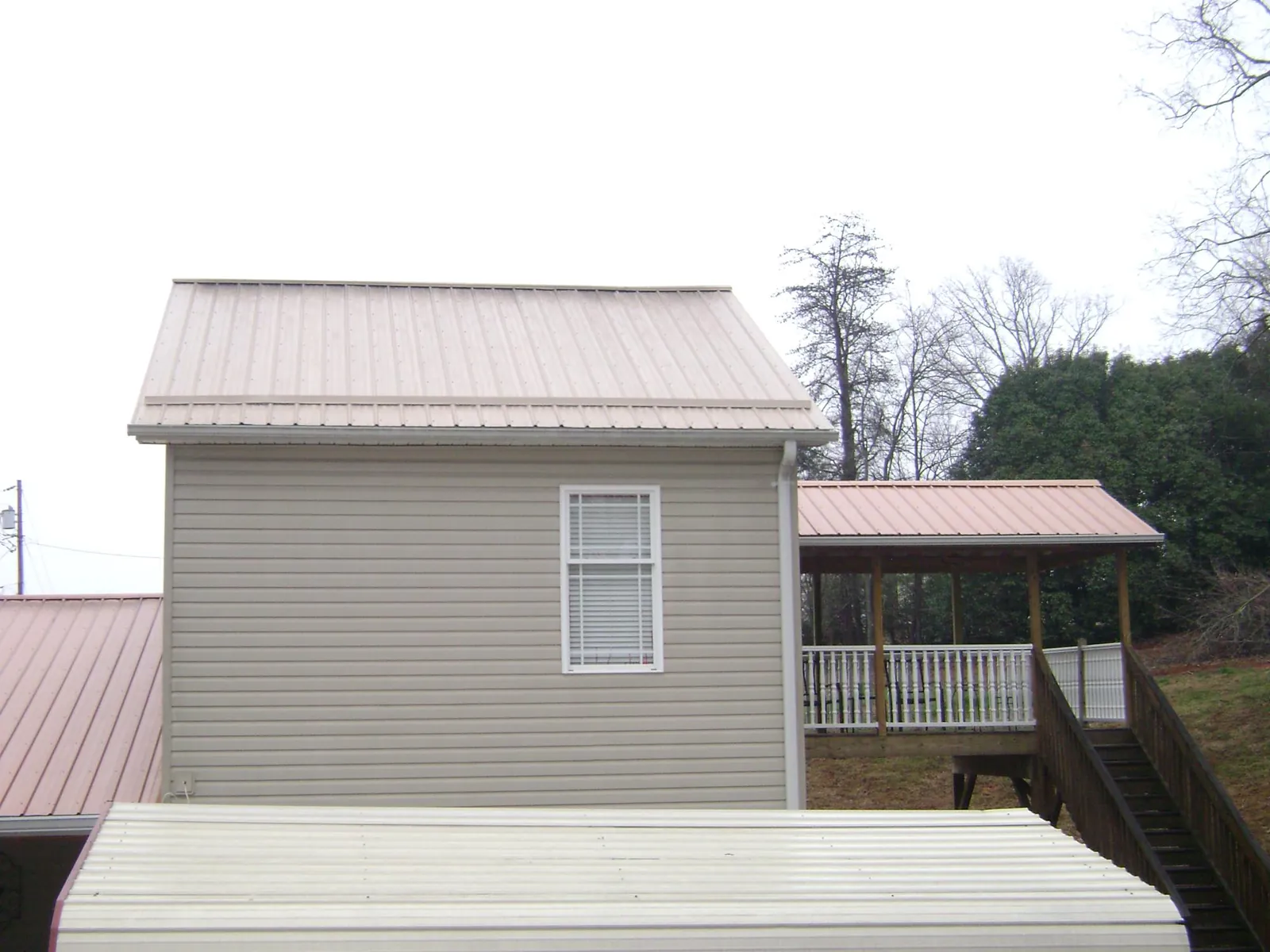 Tan metal roofs on a two story addition and attached porch, from a Roof Replacement job in Ringtown
