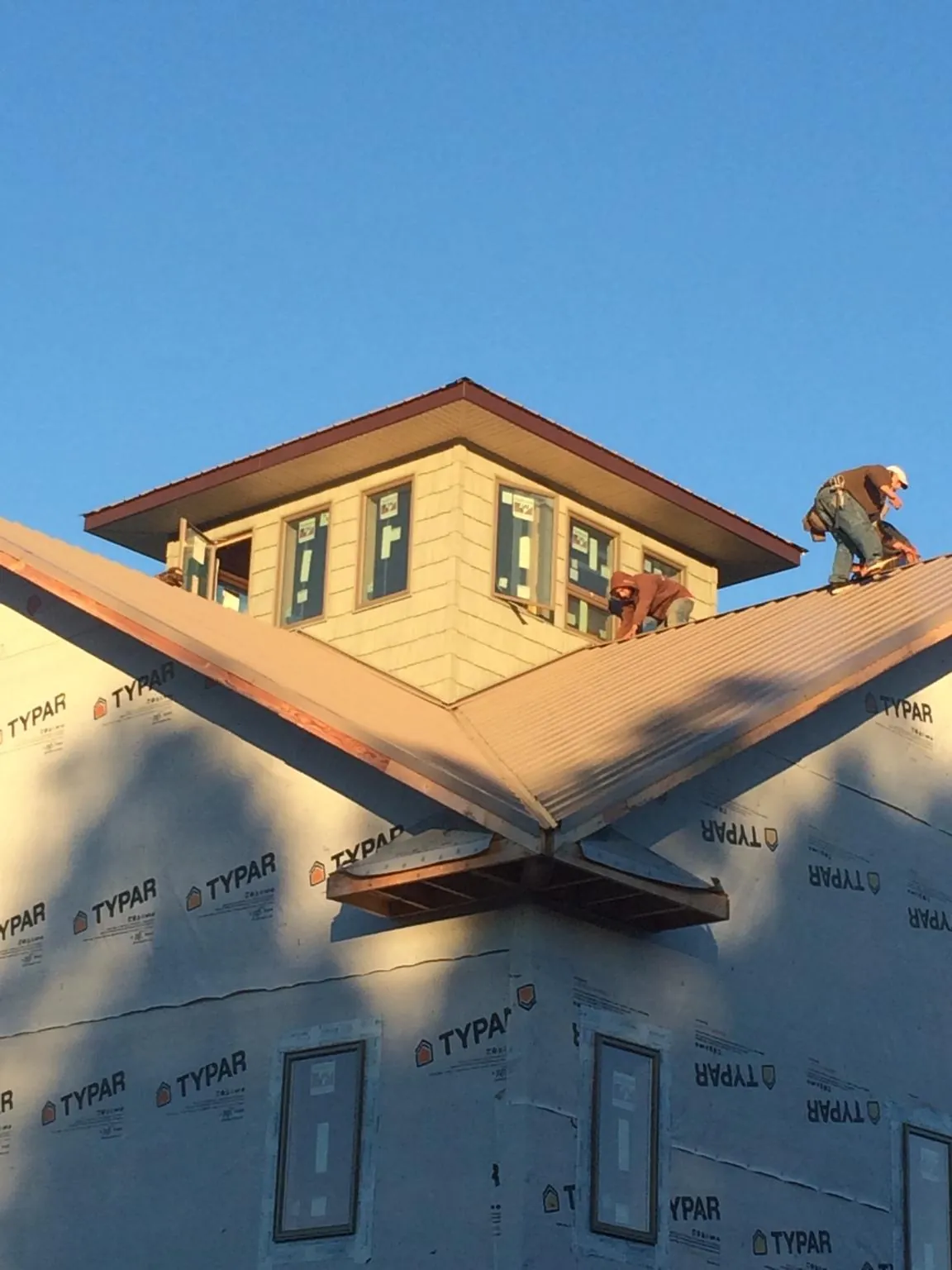 Roofers working around a rooftop cupola on a new metal roof at sunset — Roof Waterproofing in Ringtown by Roofing Brothers